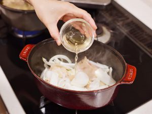 調理工程_厚手の鍋にオリーブオイル、鶏肉を皮面から入れ中火にかけ、両面に焼き色がついたら、にんにく・玉ねぎを加えて、さっと炒める